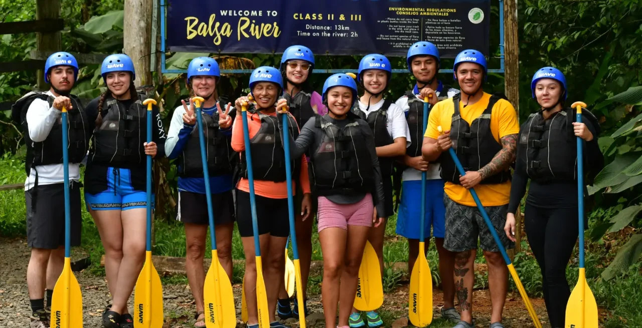 Group posing with paddles at the start of the Wave Balsa River tour