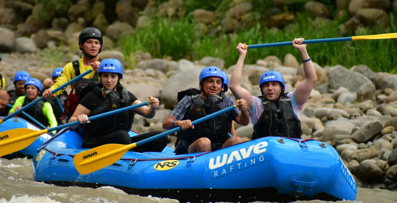 Group raising paddles while rafting on a river in Costa Rica