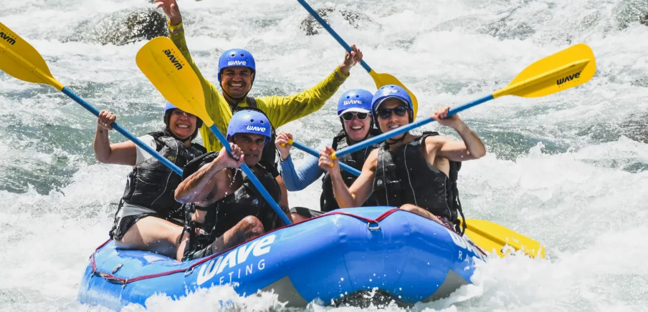 Group of rafters smiling and raising paddles during a guided rafting tour in Costa Rica