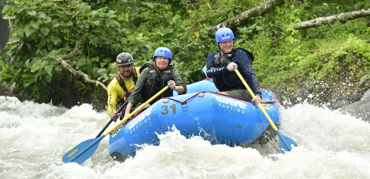 rafting group navigating a river rapid during a wave expeditions tour near arenal